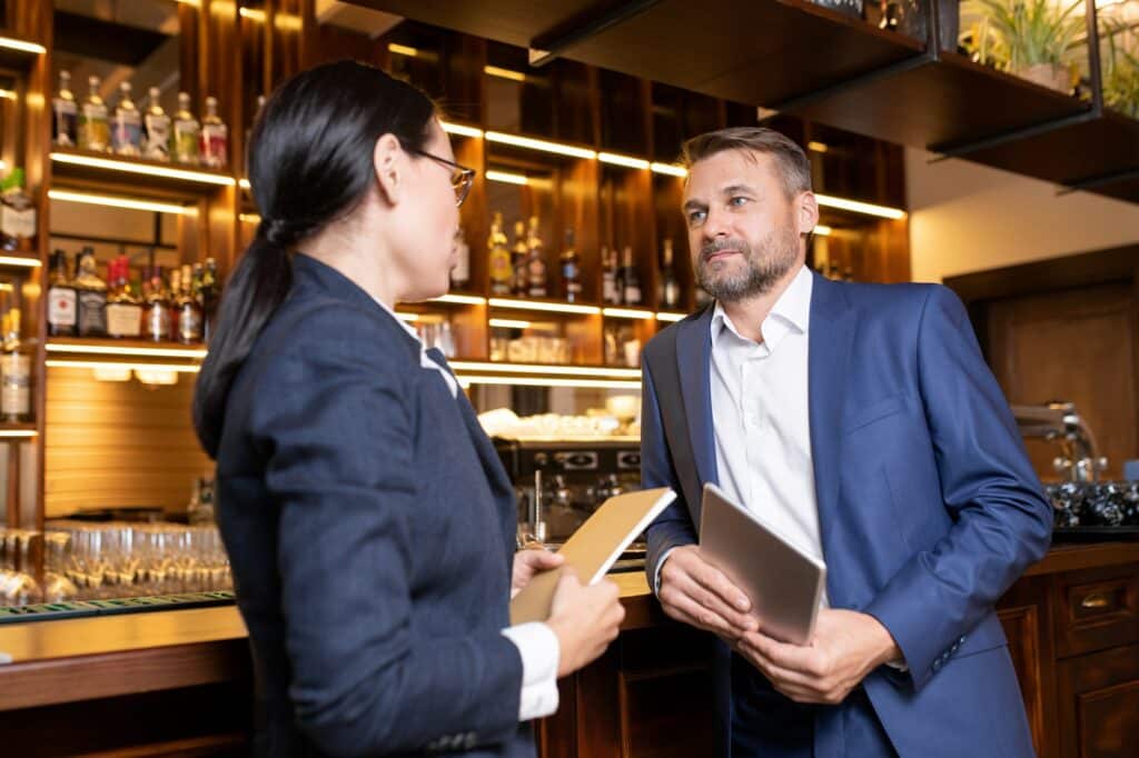 Two owners of luxurious restaurant interacting by bar counter
